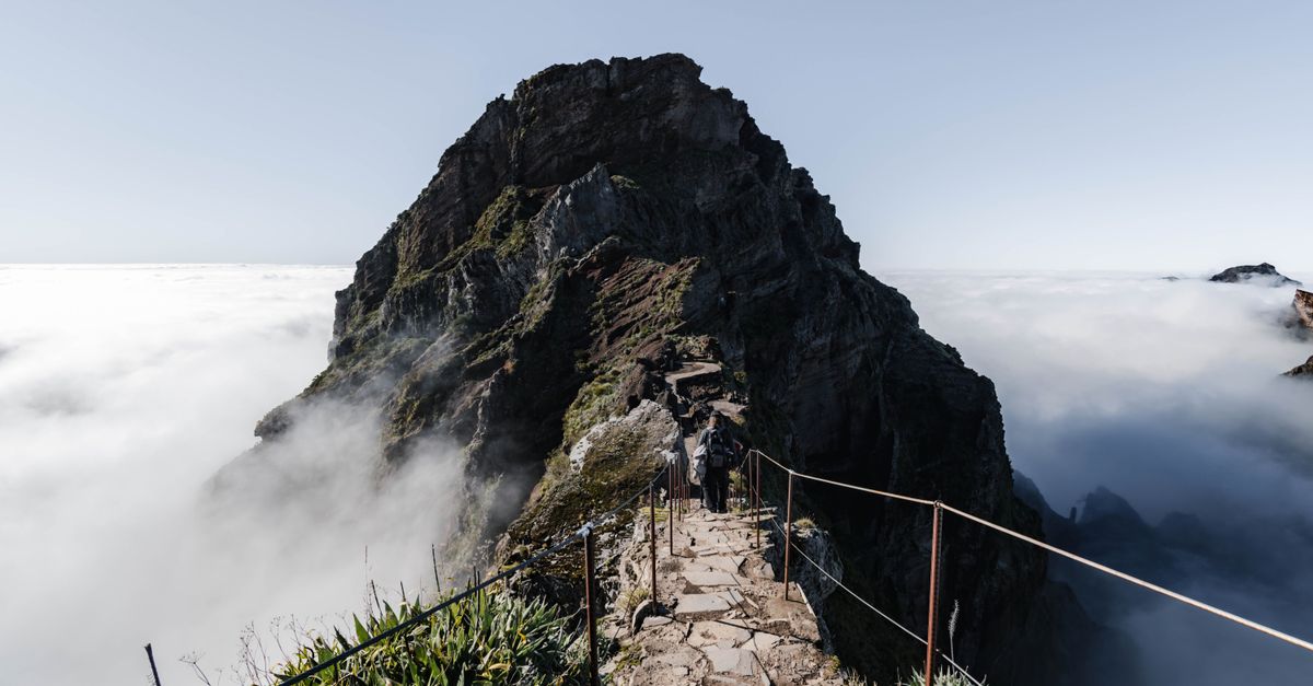 A narrow mountain path disappearing into thick fog along a rocky ridge high in Madeira’s mountains
