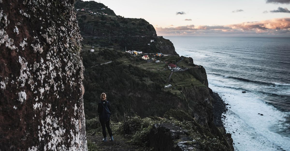 Hiker on a narrow cliff path high above Madeira's coast in the evening light